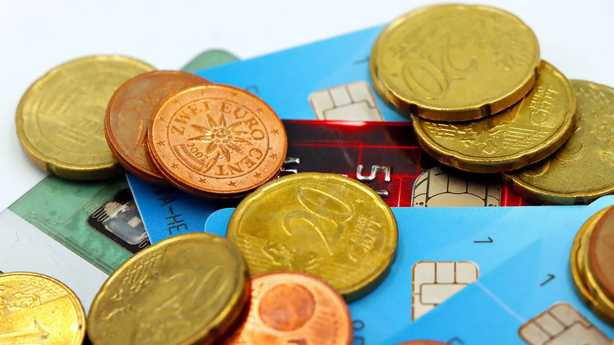 Cambiar de banco: monedas de euro sobre varias tarjetas bancarias sin marca