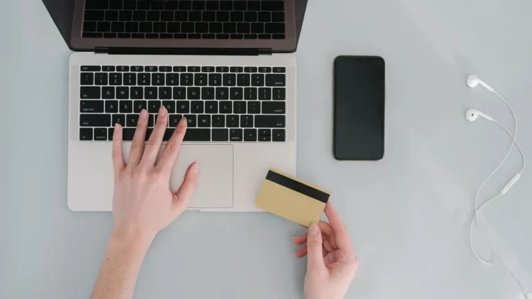CRS y Hacienda: persona gestionando su cuenta bancaria online desde el portátil con una tarjeta en la mano