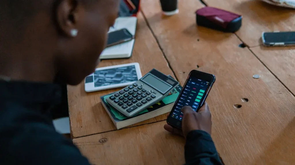 Robo-advisor: consulta de la cartera desde el móvil con una calculadora sobre la mesa