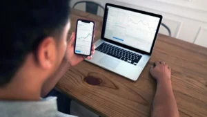 Robo-advisors en España: persona revisando la evolución de su cartera indexada en el móvil y el portátil