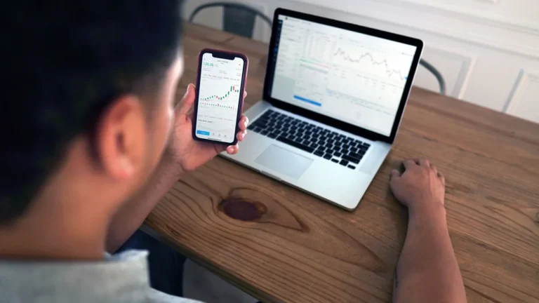 Robo-advisors en España: persona revisando la evolución de su cartera indexada en el móvil y el portátil