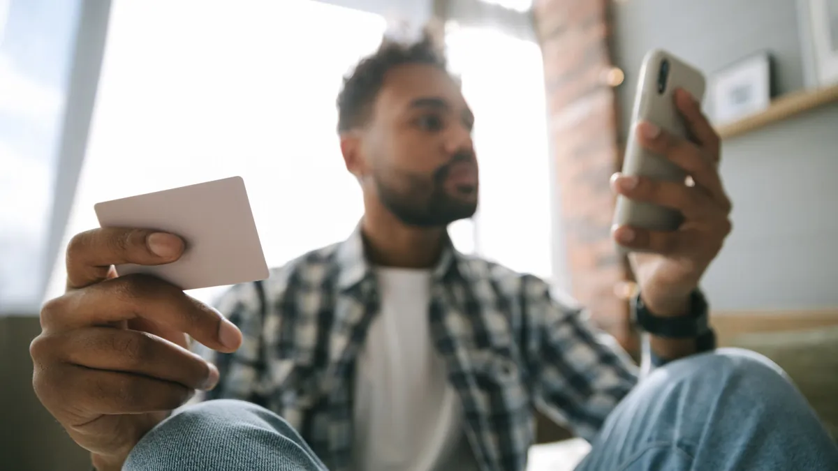 Ahorro automático desde la app: persona con el móvil y una tarjeta en la mano