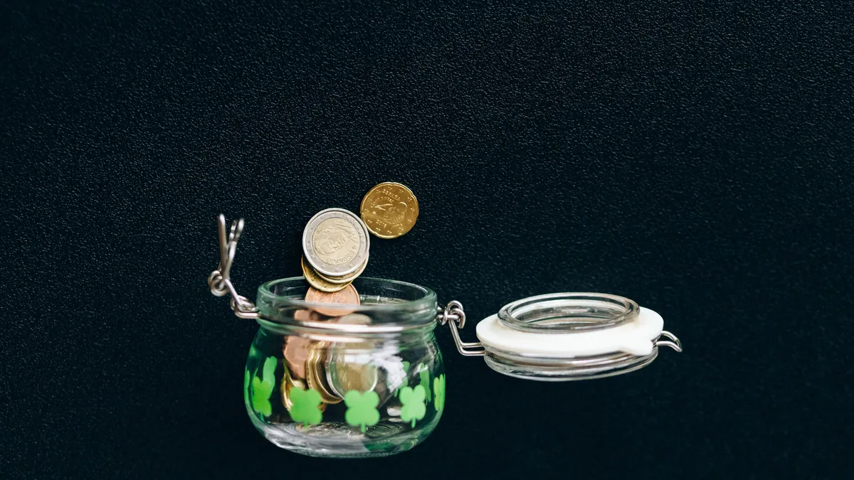 Ahorro automático: monedas de euro cayendo en un tarro de cristal