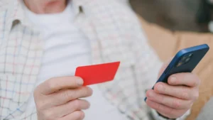 Cuentas para pensionistas: persona jubilada con su tarjeta y el móvil revisando la cuenta