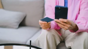 Estafas bancarias: persona con una tarjeta y el móvil en la mano antes de pagar por internet