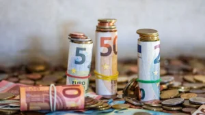 Fondo de emergencia: billetes de euro enrollados y monedas apartados como colchón de ahorro