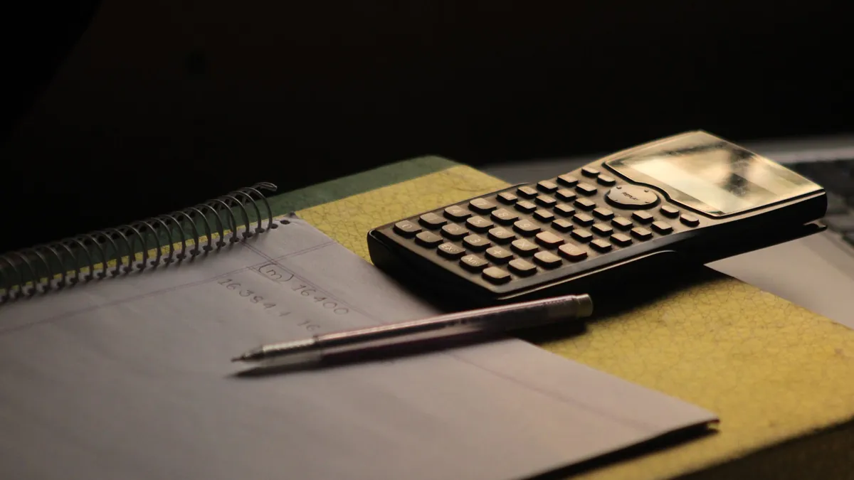 Calcular el fondo de emergencia: libreta con cuentas, calculadora y lápiz sobre la mesa
