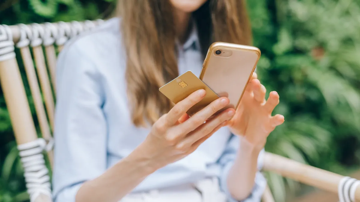 Neobanco o banco tradicional: mujer pagando con la tarjeta y la app del banco en el móvil