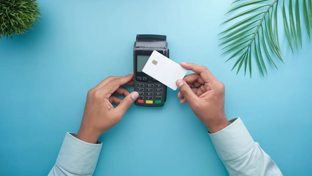 Tarjetas y pagos: manos acercando una tarjeta sin marca a un datáfono
